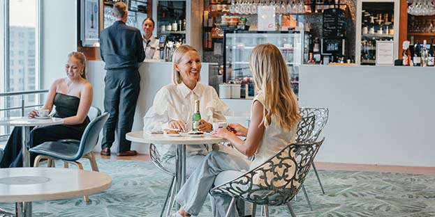 Kaksi naista hymyilee ja keskustelee p&ouml;yd&auml;n &auml;&auml;ress&auml; Bar Naissaaressa.