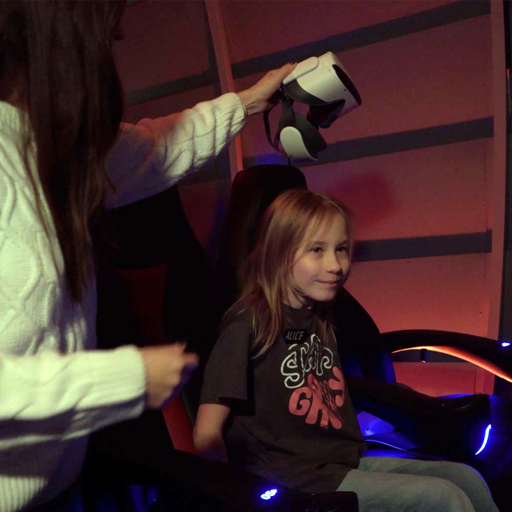 Poika istuu tuolissa ja nainen ojentaa virtuaalilaseja.