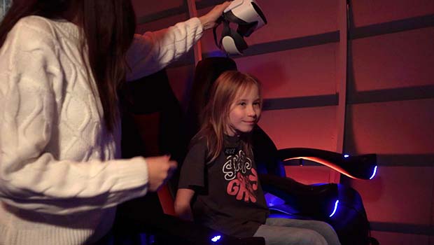 Poika istuu tuolissa ja nainen ojentaa virtuaalilaseja.