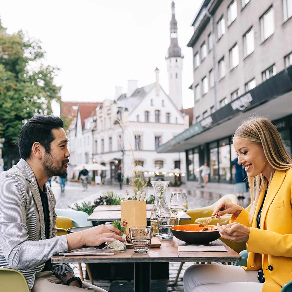 Mies ja nainen ruokailevat ulkona ravintolan terassilla Tallinnassa.
