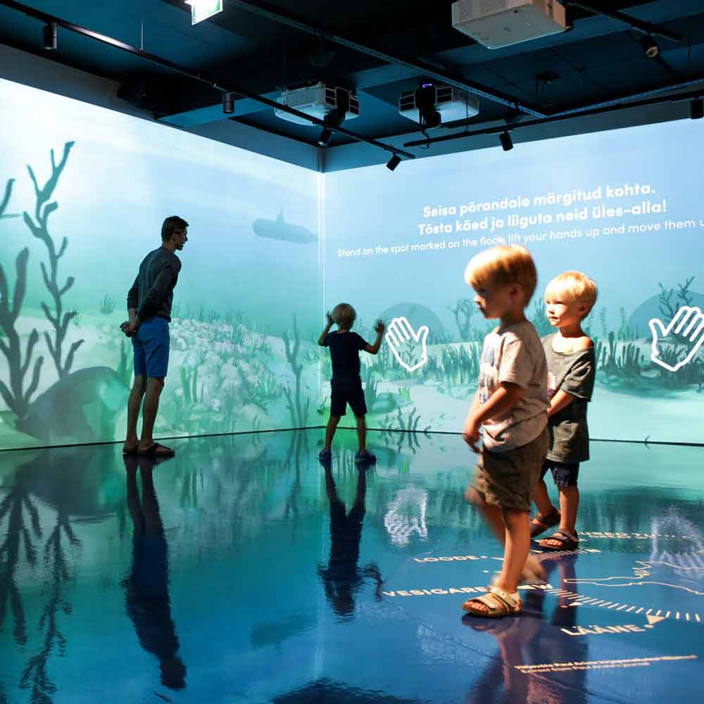 Kaksi alle kouluikäistä poikaa tutkii modernia museotilaa. Sen seinät ovat kuin kuva merenpohjasta.